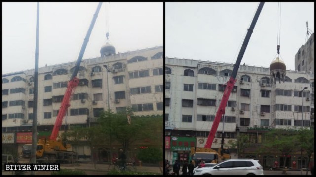 크레인이 건물 상단의 원형 이슬람 구조물을 해체하고 있다