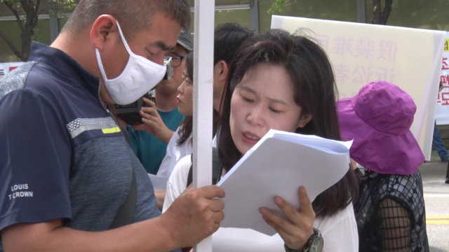 시위 중에 어느 전능신교 신자의 가족과 함께 대본을 확인하는 오명옥 씨